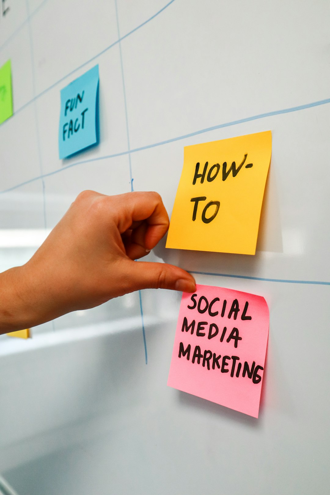 A person places a post-it note onto a whiteboard that reads Social Media Marketing